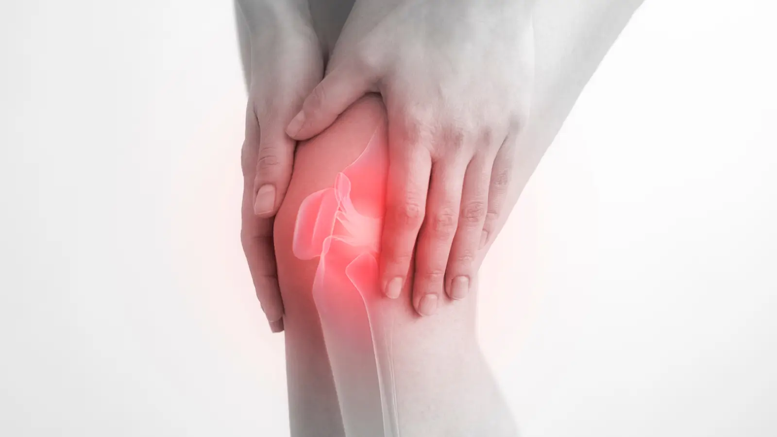 A person holding their knee with visible redness, indicating pain or inflammation.