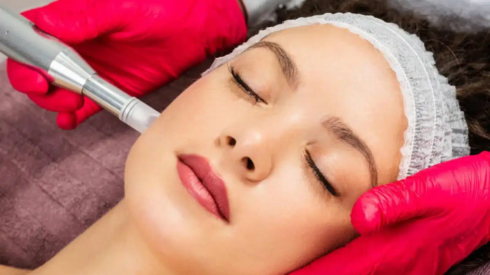 A woman relaxing as a healthcare professional massages her face following filler treatment.