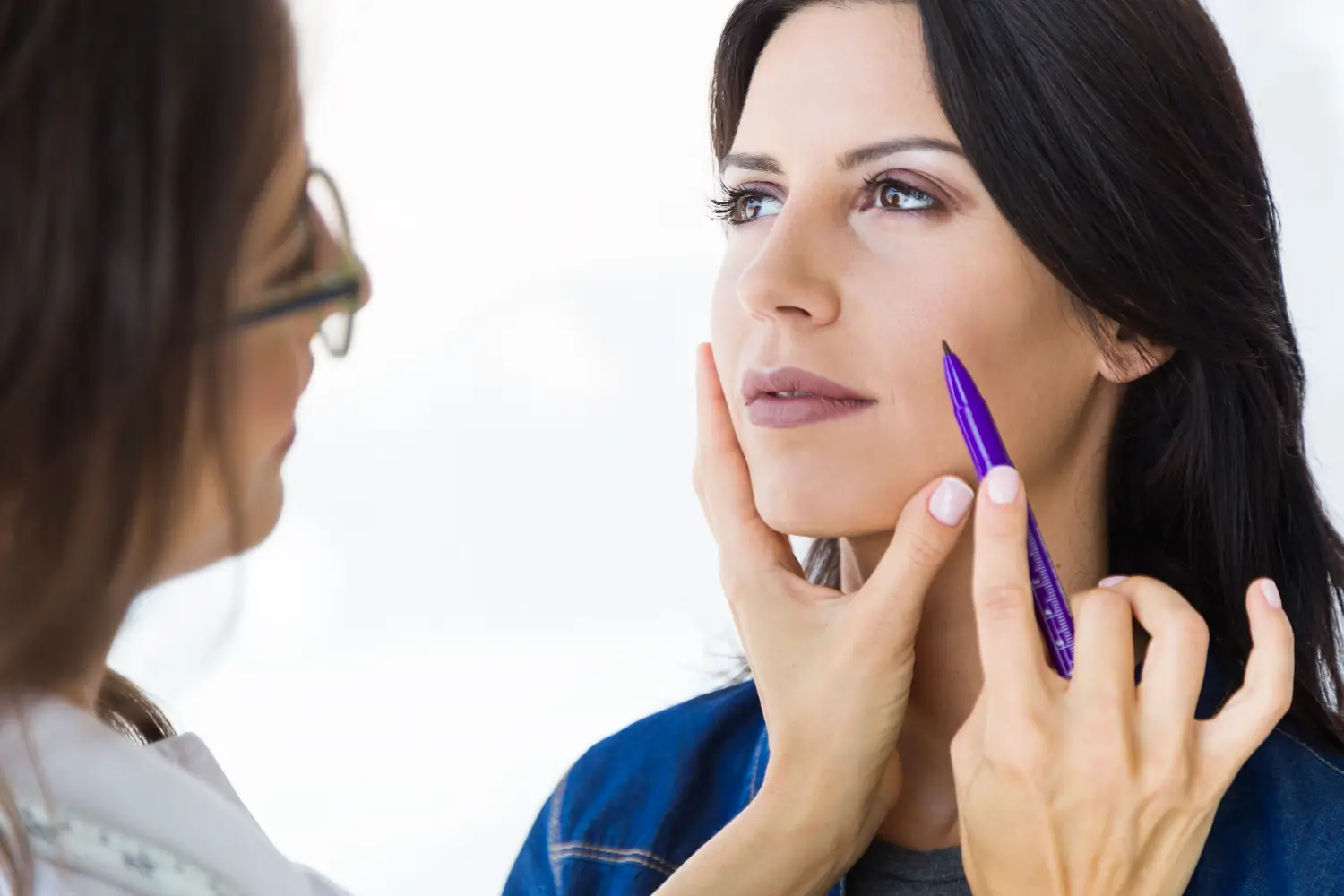 Woman with a pen near her face.