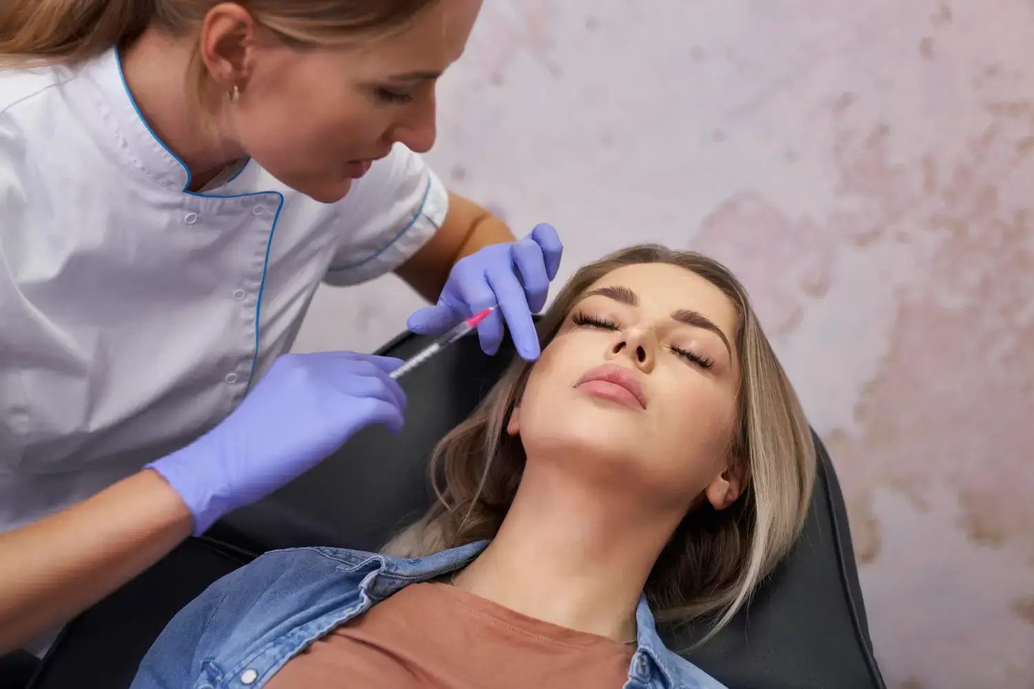 A healthcare professional carefully administers a Neuramis filler injection to a woman's face as she reclines in the chair.