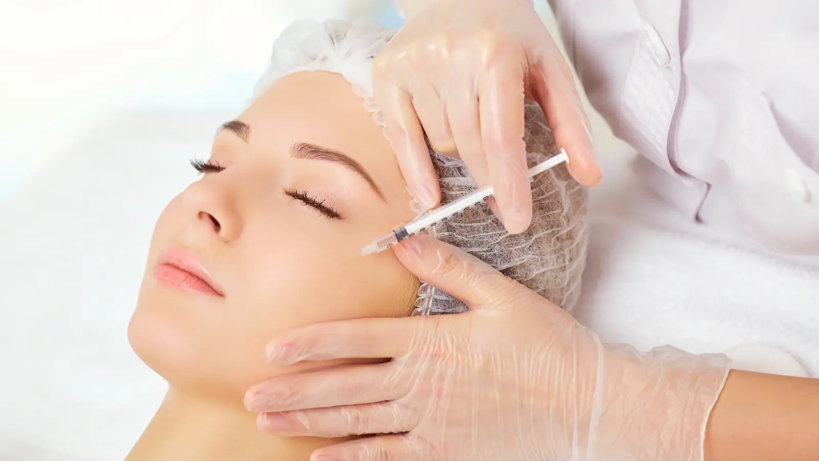 A female patient receives filler injection for the face in a clinical setting.